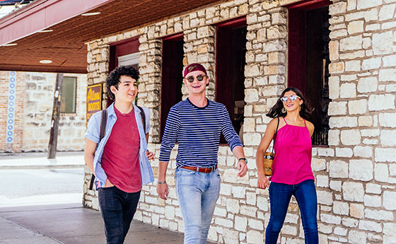 Three students walking along south congress in front of Allen's boots