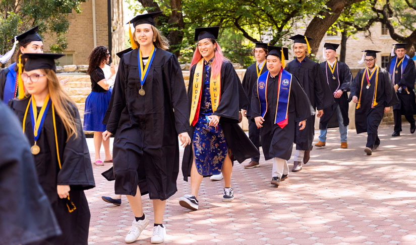 St. Edward's graduates walk toward Main Building during Legacy Walk