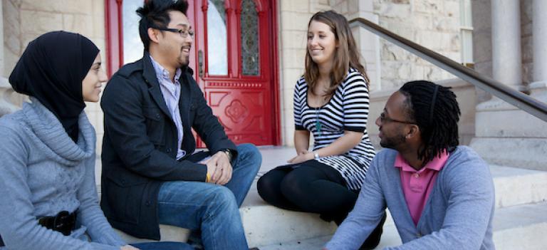 Four students on stairs to Main Building