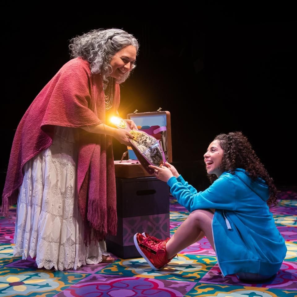 Actor playing Abuela hands wrestling belt to Granddaughter