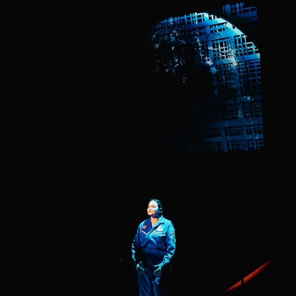 Actor in Walden with a projection of the Earth behind her. 