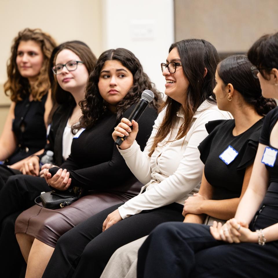 Six female students sit in a row wearing professional attire.
