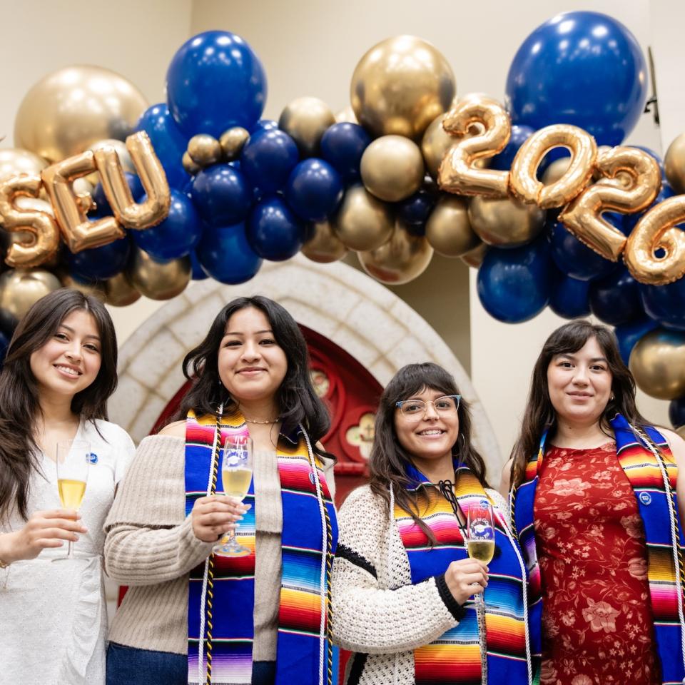 Four students celebrating a First generation event with apple cider wine flutes
