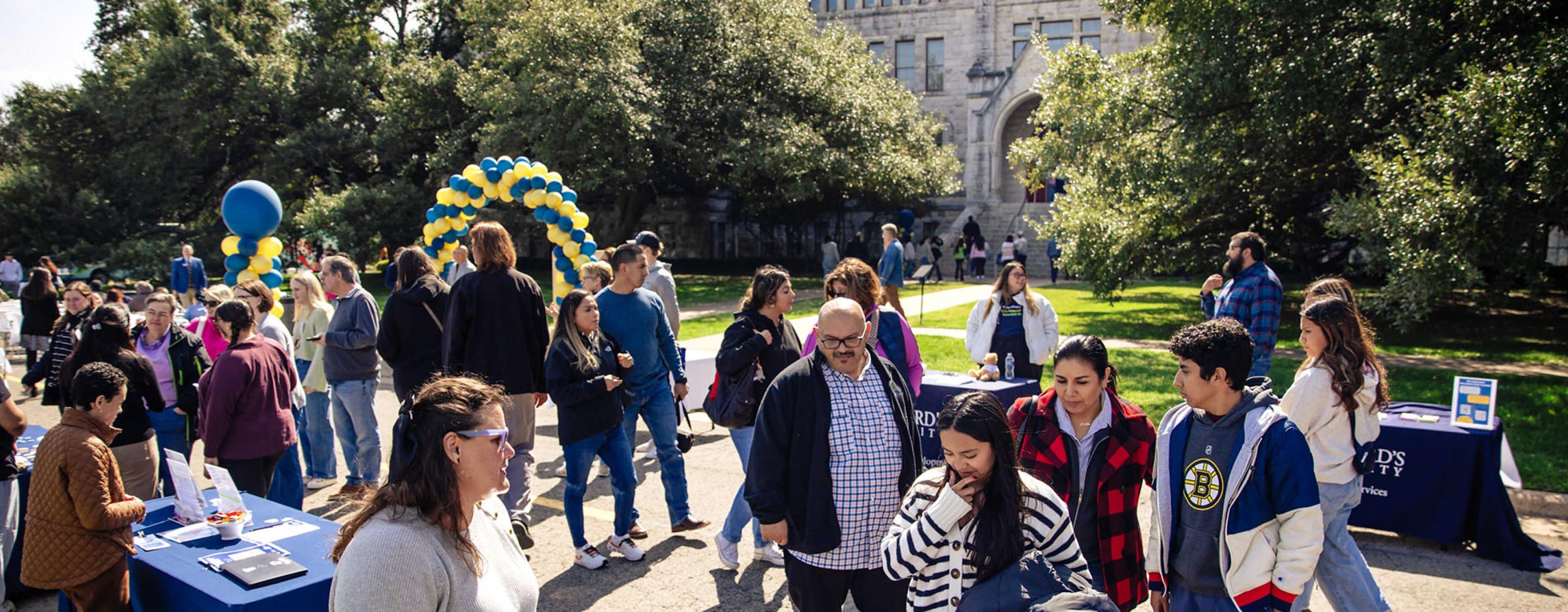 Students explore clubs and organizations at various tables in front of Main Building on the St. Edward's University campus