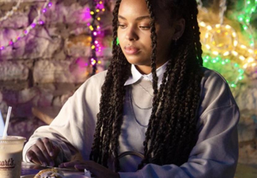 Person sitting at a table with colorful lights hanging behind them.