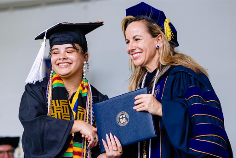 Kaitlynn Devitt (left) receives her degree at graduation. Devitt was awarded the Michele Kay Outstanding Journalist Award for her photojournalism work.