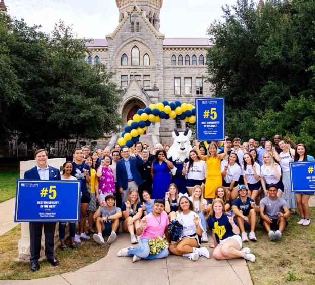 President Fuentes and students holding signs and balloons to celebrate St. Edward's being the #5 University in the West