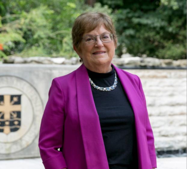 A photo of a woman standing wearing a purple jacket