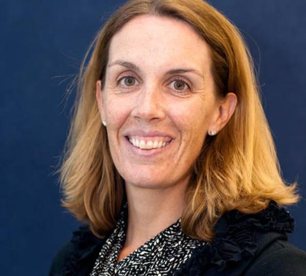 A headshot of a woman smiling as medium length hair