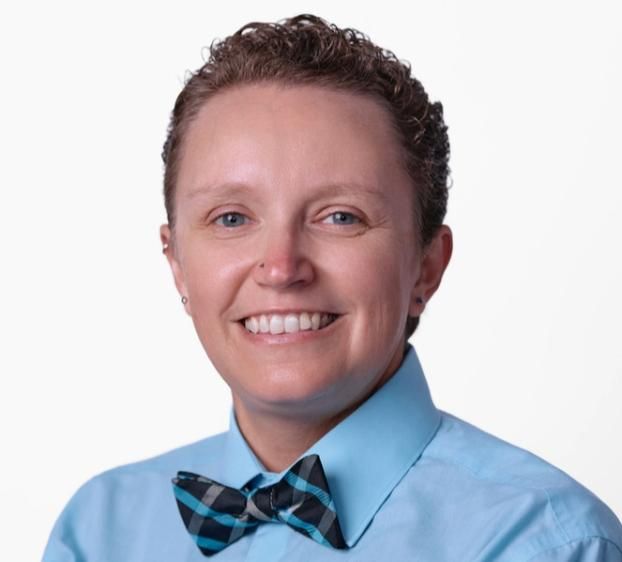 A photo of a person smiling and with a tie bow.