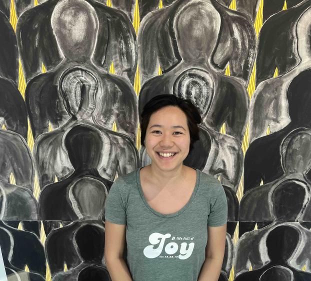 A photo of a woman standing in front of art work