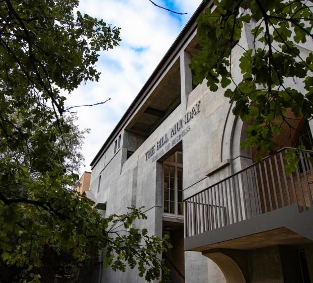 A beige building with letters that read "The Bill Munday School of Business"