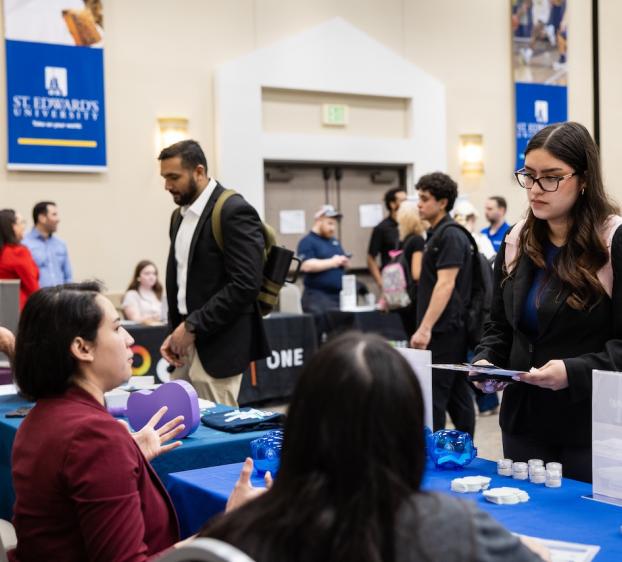 Students and employers gather for a career fair in a ballroom. 