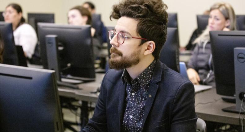 student in a blue shirt in front of a computer in class