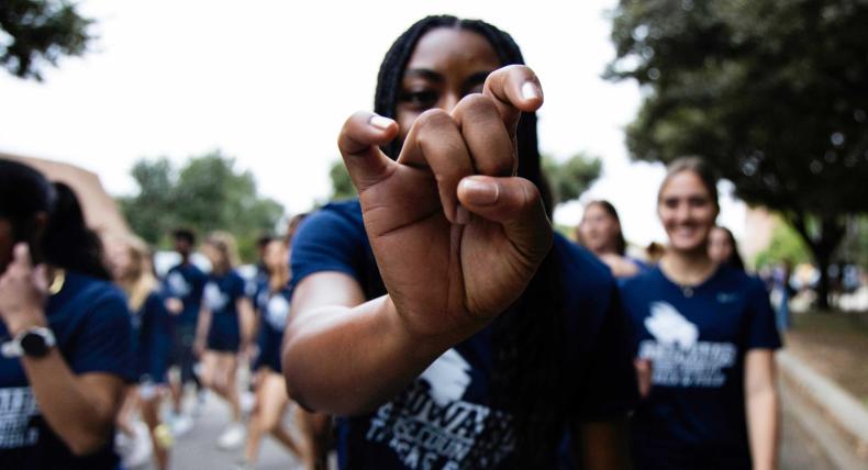A student does Toppers Up hand sign during Homecoming