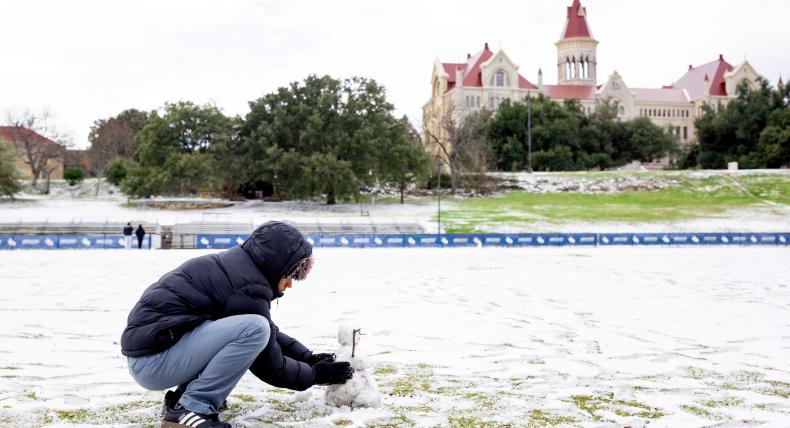 A student builds a snowman on the soccer field during the January 2025 snow day in Austin.