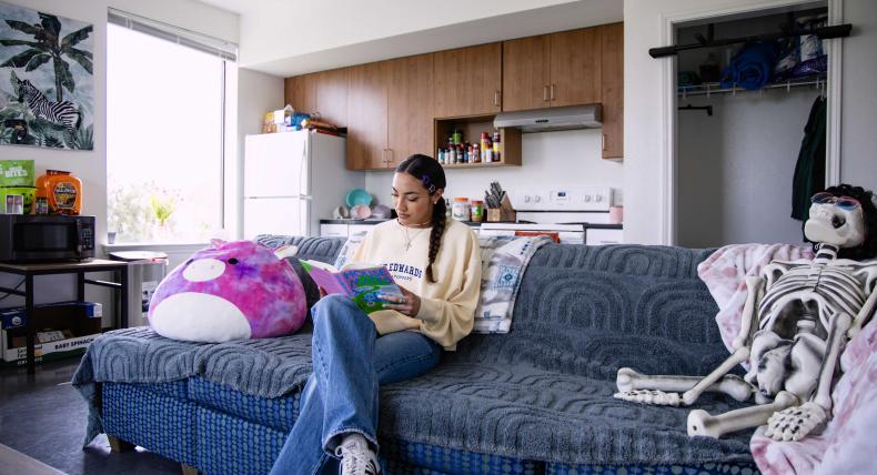 Student sitting in their dorm reading.