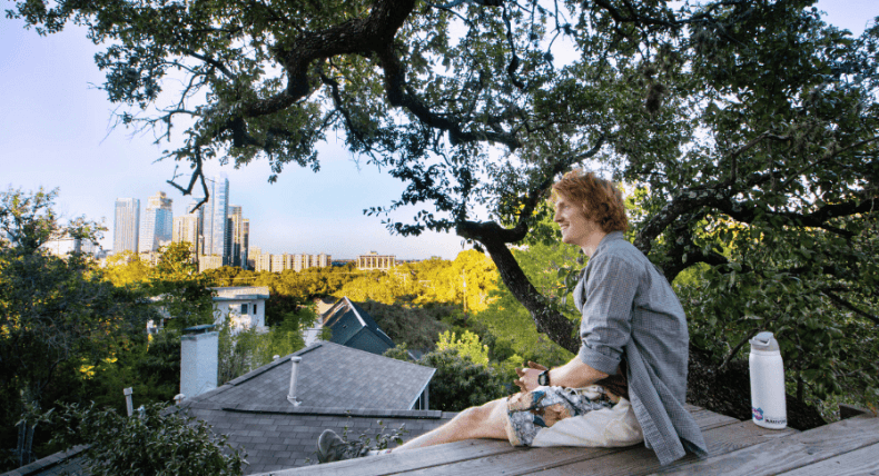 Ethan Burd sits on his home treehouse with a view of the Austin skyline