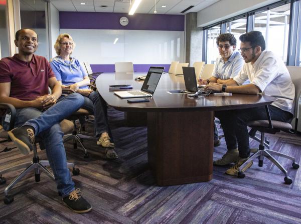2 students sitting at a board room table at their internship with two supervisors.