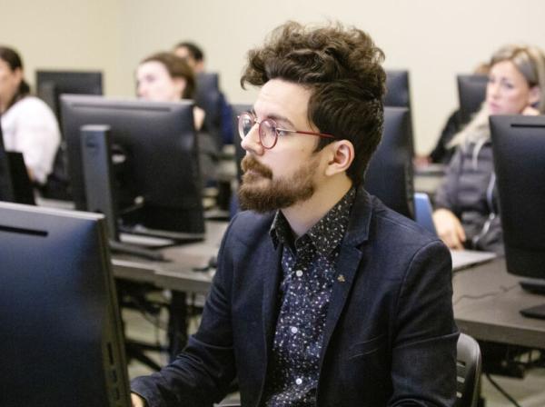 student in a blue shirt in front of a computer in class