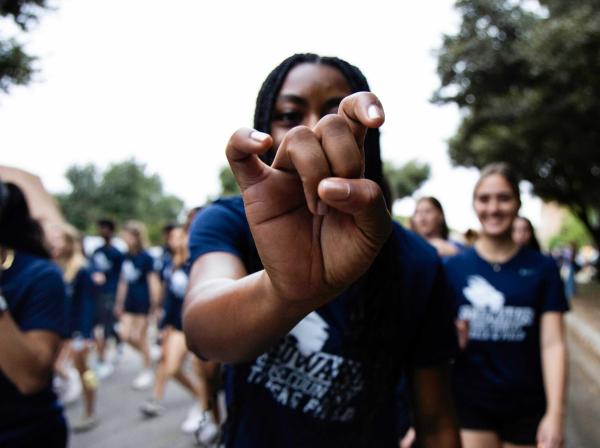 A student does Toppers Up hand sign during Homecoming