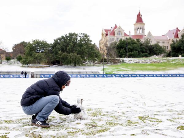 A student builds a snowman on the soccer field during the January 2025 snow day in Austin.