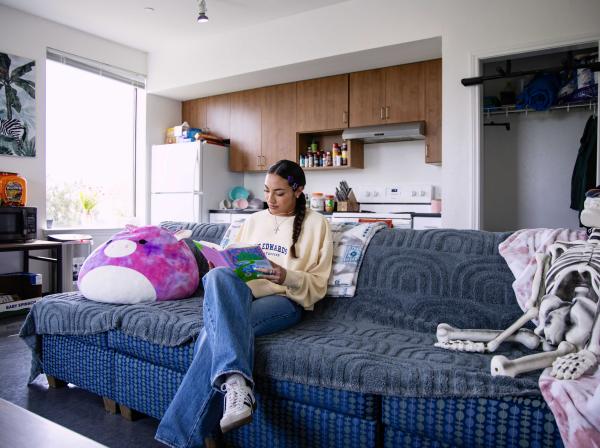 Student sitting in their dorm reading.
