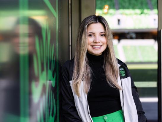 Emely Alvarado standing next to an Austin FC sign
