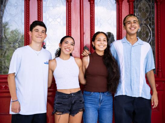 New students standing outside the red doors of main building