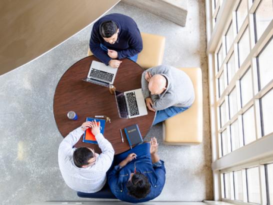 Students gather around a table to study in The Bill Munday School of Business.