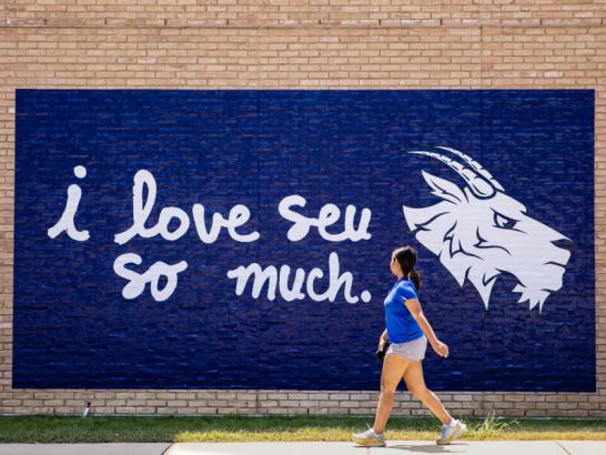 A student walks in front of the "i love seu so much" 
