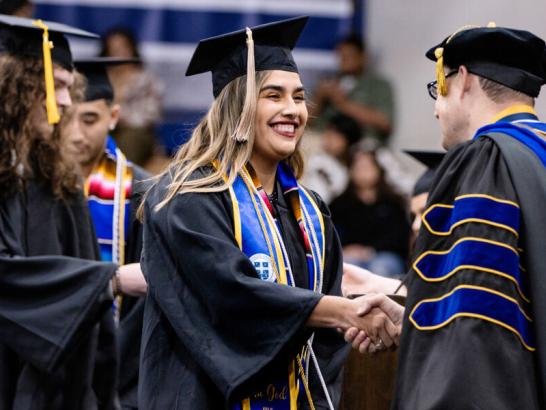 Graduate receiving diploma at December graduation