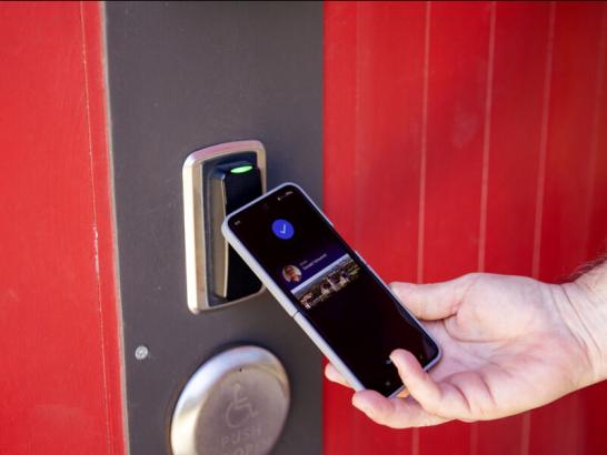 Someone using the Hilltopper Card app on their phone to unlock a doot