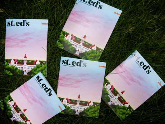 Five copies of the St. Ed's magazine are shown on the grass from an aerial viewpoint