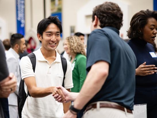 Two men dressed business casual shake hands. 