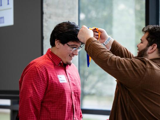 Student wearing red shirt receiving McNair medallion at ceremony