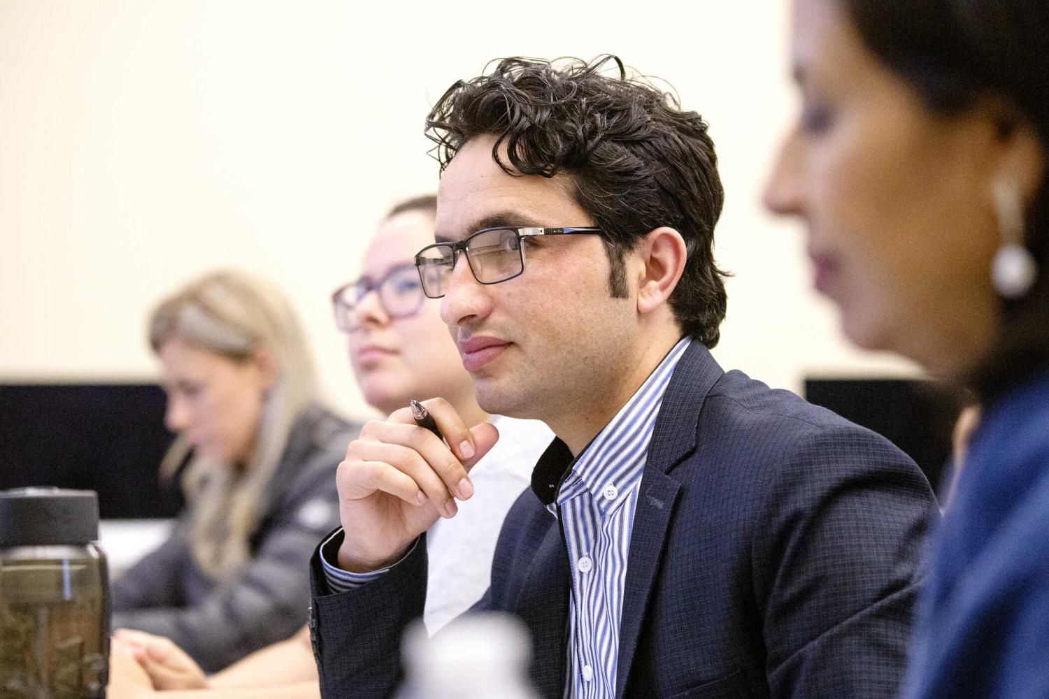 Graduate students attentively listening and taking notes during a lecture at St. Edward's University.