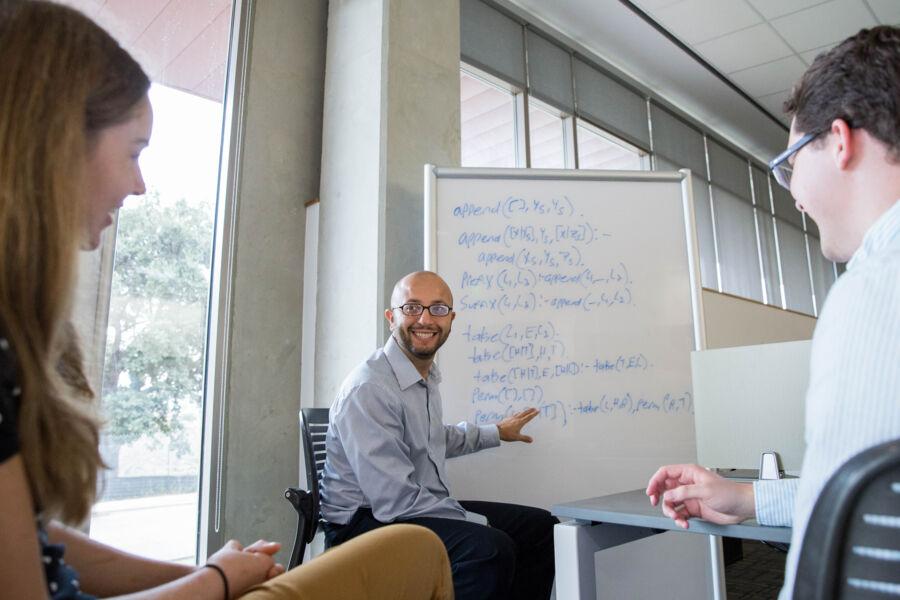 Professor Shebaro points to information on a white board and two students listen to his instruction. 