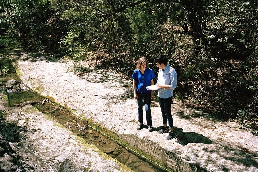 Professor Teresa Bilinksi and Justin Stewart discuss research near a creek.