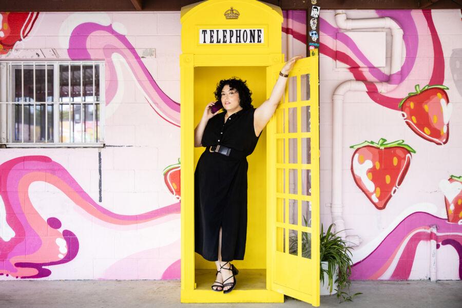 Fabiana Melendez poses in a yellow telephone booth