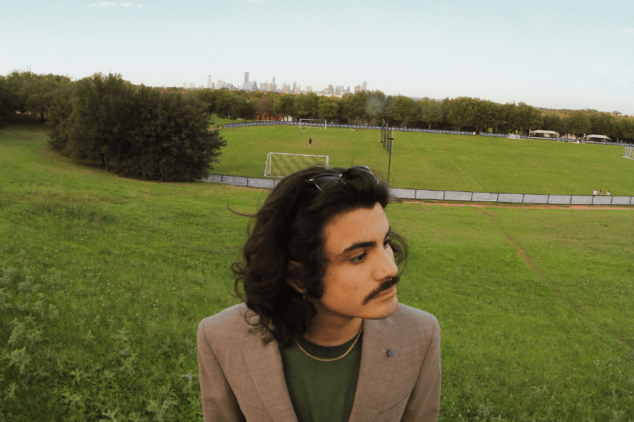 Student poses in front of the skyline for music artwork