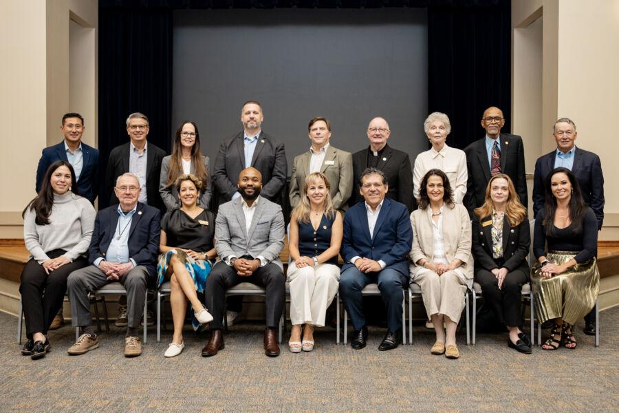 The Board of Trustees and President Fuentes posing in front of a stage