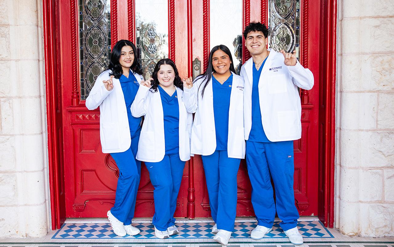 Nursing students posing for a photo in front of the Red Doors at Main Building.