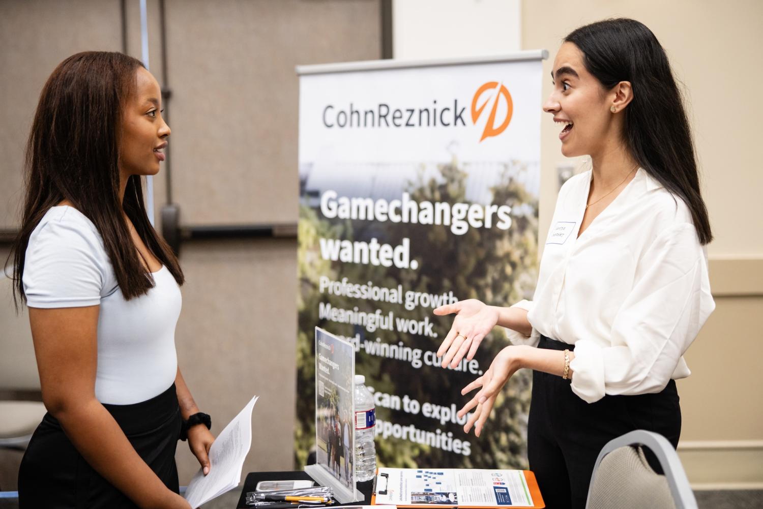 Two women network at a career fair.
