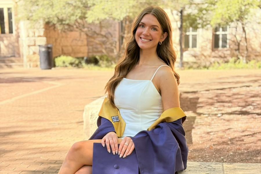 Avery Henderson '26 poses in her cap and gown for graduation near Main Building.